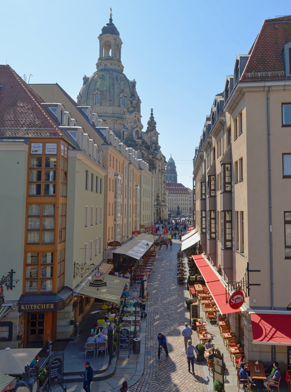 5 - Münzgasse street in Dresden, Germany, featuring outdoor restaurant seating along the cobblestone path and the iconic dome of the Frauenkirche rising in the background